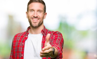 Yakışıklı adam rahat gömlek giyen tebrik ve karşılama olarak el sıkışma sunan dostu gülümseyerek. Başarılı iş.