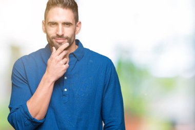 Yakışıklı delikanlı emin çapraz kollar ve çeneme kaldırdı el ile gülümseme ile kameraya bakarak izole arka plan üzerinde. Pozitif düşünce.