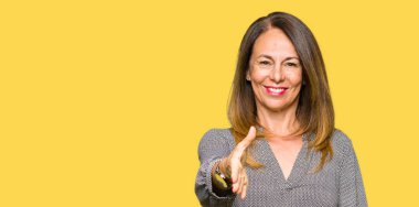 Tebrik ve konuksever dost sunan karşılıklı gülümseyen güzel orta yaş bir iş kadını. Başarılı iş.