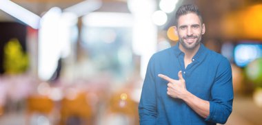 Yakışıklı delikanlı izole arka neşeli bir gülümseme ile el ve parmak kadar yan yüzünde mutlu ve doğal ifade ile işaret yüz üzerinden