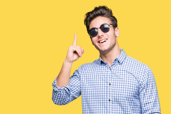 Mladý Pohledný Muž Nosí Sluneční Brýle Přes Izolované Pozadí Ukazováčkem — Stock fotografie