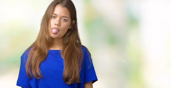 若い美しいブルネット女性の舌を付着分離の背景に青い シャツを着てアウト面白い表現に満足 感情の概念 — ストック写真