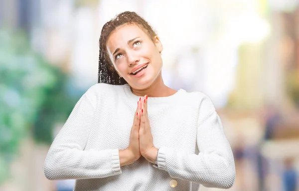 Young braided hair african american girl wearing winter sweater over isolated background begging and praying with hands together with hope expression on face very emotional and worried. Asking for forgiveness. Religion concept.