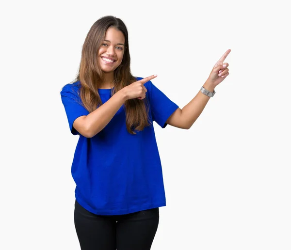 年轻美丽的黑发女人穿着蓝色 T恤在孤立的背景微笑着 看着相机指向用两只手和手指的一侧 — 图库照片