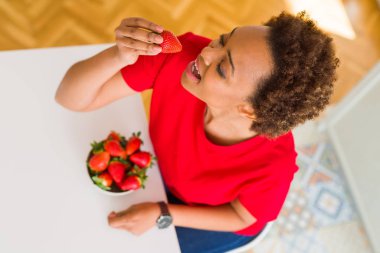 Güzel genç Afro-Amerikan kadın taze kırmızı strawber yeme