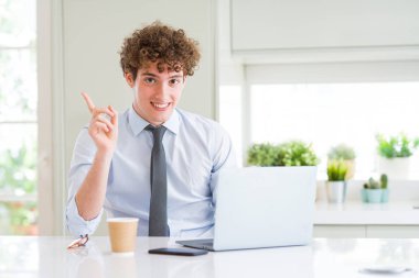 Ofiste bilgisayarla çalışan genç bir iş adamı elini ve parmağını yan tarafa uzatmaktan çok mutlu olur.