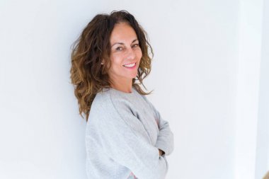 Kıvırcık saçlı güzel orta yaş kadın, beyaz izole arka plan üzerinde dişleri gösteren yüzünde büyük bir gülümseme ile gülüyor, silah geçti neşeli ve mutlu gülümseyen