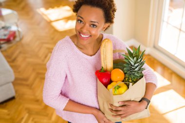 Kağıt torba dolu tutan genç güzel Afrikalı-Amerikalı kadın