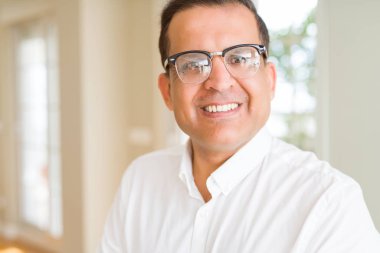 Evde kameraya gülümseyen gözlük takan orta yaş erkek