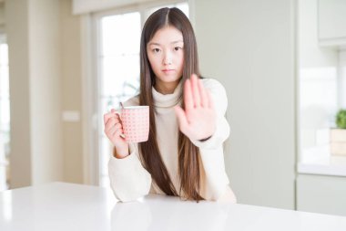 Güzel Asyalı kadın açık el ile ciddi ve emin ifade, savunma jest stop işareti yapıyor bir fincan kahve içme