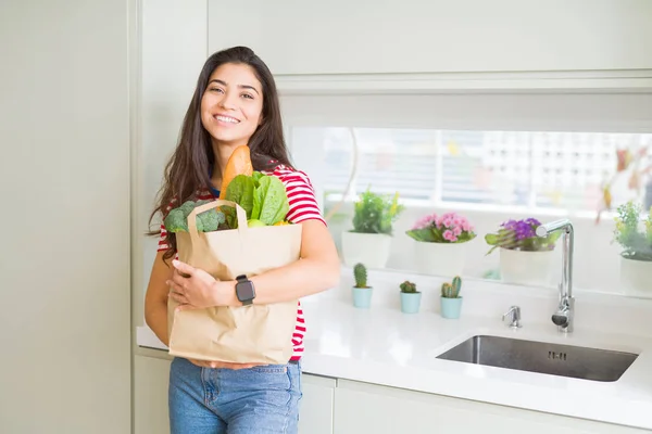 Mooie jonge vrouw glimlachend het houden van een papieren zak vol kruidenier — Stockfoto