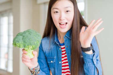 Güzel Asyalı kadın Yeşil taze brokoli çok mutlu ve heyecanlı yeme, kazanan ifade zafer büyük gülümseme ile çığlık kutluyor ve el kaldırdı