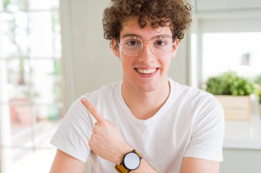 Gözlük neşeli bir gülümseme ile el ve parmak kadar yan yüzünde mutlu ve doğal ifade ile işaret yüz genç yakışıklı adam