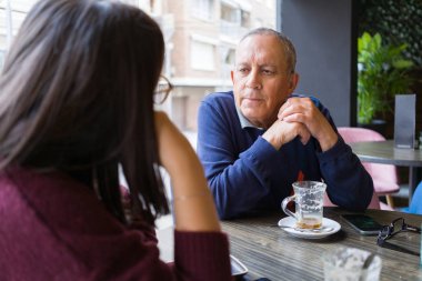 Kadın kahve içme ve rahatlatıcı, restoranda sohbet ile bir konuşma sahip kıdemli adam
