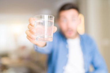 Genç yakışıklı adam evde bir bardak su içme sürpriz bir yüz ile şok korkmuş, korku ifade korku ve heyecanlı