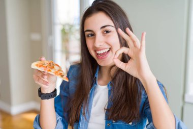 Güzel genç kadın parmakları ile ok işareti yapıyor lezzetli pizza bir dilim yemek, mükemmel sembolü