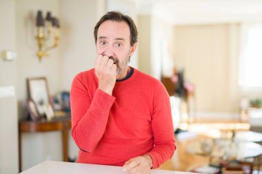 Yakışıklı orta yaş erkek evde stresli ve gergin elle çivi ısırma ağzına bakıyor. Anksiyete sorunu.