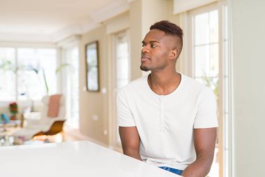 Yakışıklı afro-amerikan adam evde beyaz masada yan bakıyor, kendine güvenen gülümseme ile doğal yüzü ile profil poz dinlenmek.
