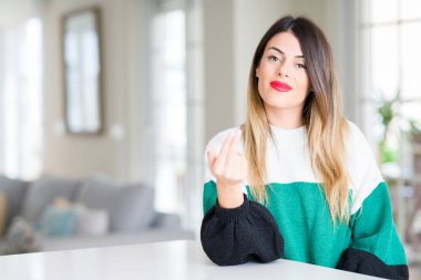 Genç güzel kadın giyiyor kış kazak evde Beckoning gel burada mutlu ve gülümseyerek el davet ile jest