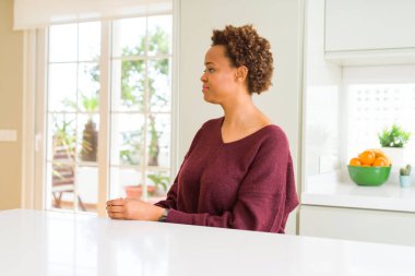 Genç güzel Afrikalı-Amerikalı kadın evde doğal yüz emin gülümseme ile pozuyla profil rahatla tarafına, seyir.