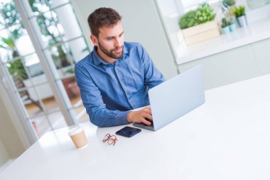 Yakışıklı iş adamı çalışma kullanma bilgisayar dizüstü ve gülümseyen