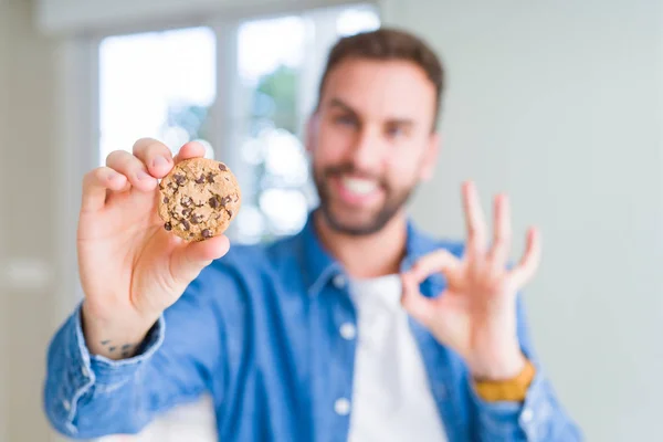 Beau Homme Mangeant Des Biscuits Aux Pépites Chocolat Faisant Signe — Photo