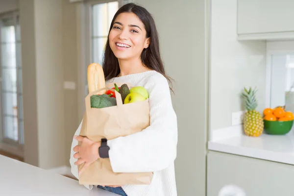 食料品店でいっぱいの紙袋を持って微笑む美しい若い女性 — ストック写真