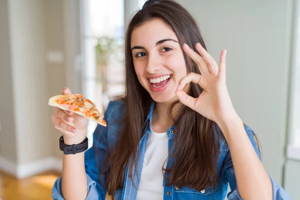 Piękna Młoda Kobieta Jedzenia Kawałek Smaczne Pizzy Robi Znak Palcami — Zdjęcie stockowe