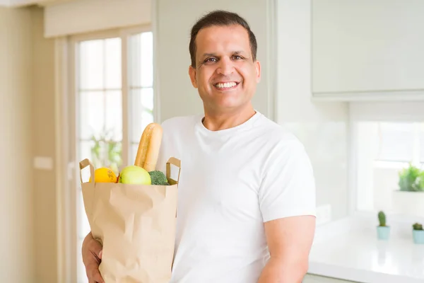 Homem de meia idade segurando grocieries saco cheio de legumes em casa — Fotografia de Stock