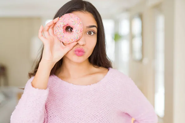美丽的年轻女子看通过粉红色的甜甜圈的眼睛发送 — 图库照片