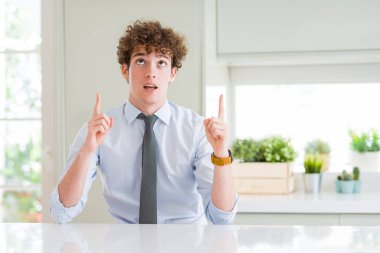 Bir kravat giyen genç iş adamı şaşırttı ve şaşırttı yukarı bakarak ve parmakları ile işaret ve kollarını kaldırdı.