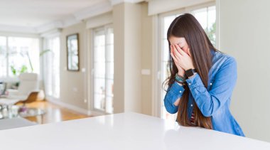 Uzun saçlı Genç güzel Asyalı kadın ağlarken elleri ile yüz kapsayan üzücü ifade ile denim ceket giyiyor. Depresyon konsepti.