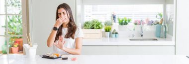 Geniş açılı fotoğrafta, Asya suşisi yiyen güzel bir kadın pis ve iğrenç bir koku alıyor, nefesini burnunda tutuyor. Kötü koku konsepti.