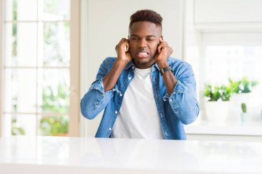 Yakışıklı afro-amerikan adam evde yüksek sesle müzik sesi için rahatsız ifade ile parmakları ile kulakları kapsayan. Sağır kavramı.