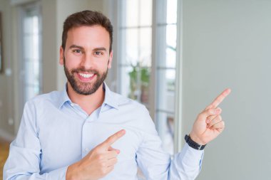 Gülümseyen ve iki elleri ve parmakları ile tarafına işaret kamera bakarak yakışıklı iş adamı.