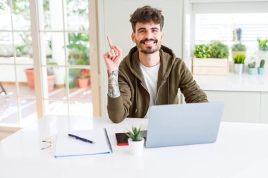 Bilgisayar laptop ve defter el ve parmak ile tarafına işaret çok mutlu kullanan genç öğrenci adam