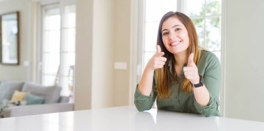 Evde mutlu ve komik yüzü ile kameraya parmaklarını gösteren güzel genç kadın. İyi enerji ve titreşimler.