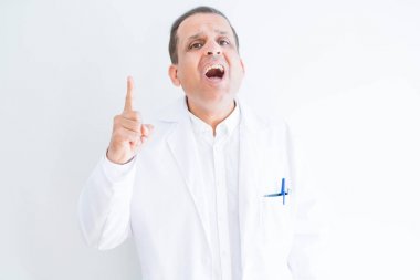Orta yaş Doktor adam beyaz arka plan üzerinde başarılı bir fikir parmak yukarı işaret tıbbi ceket giyiyor. Çıkıldı ve mutlu. Bir numara.