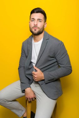 Possing oturan ve sarı izole arka plan üzerinde modelleme yakışıklı delikanlı