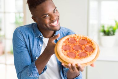 Holding Afrika yakışıklı genç ve gururlu ev yapımı biberli pizza gülümseyen gösterme