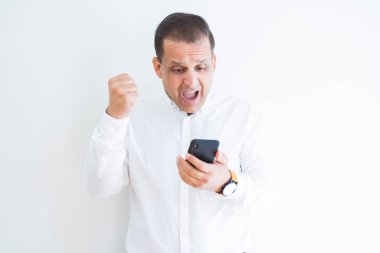 Orta yaş adam gurur çığlık ve zafer ve başarı çok heyecanlı, tezahürat duygu alkışlayan beyaz duvar üzerinde Smartphone kullanarak