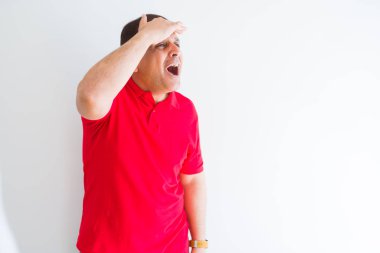 Orta yaş adam beyaz duvar üzerinde kırmızı t-shirt giyiyor çok mutlu ve gülümsüyor uzağa baş el ile bakıyor. Arama konsepti.