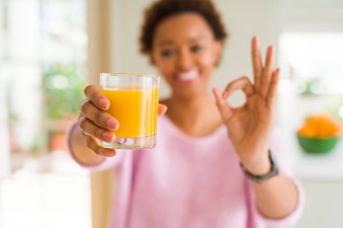Genç Afrikalı Amerikan kadın ev parmaklarıyla ok işareti yapıyor portakal suyu elsanatı, mükemmel sembolü