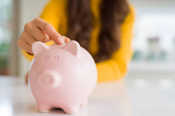 Close-up de mulher colocando uma moeda dentro do banco porquinho como investimento — Fotografia de Stock