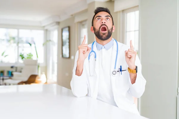 Guapo Médico Hispano Vestido Con Estetoscopio Clínica Asombrado Sorprendido Mirando —  Fotos de Stock