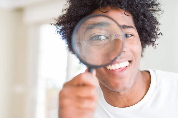 非洲裔美国男子透过放大镜看着 一张幸福的脸站着 面带微笑 露出自信的微笑 露出牙齿 — 图库照片