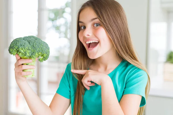 美丽的年轻女孩吃新鲜的花椰菜非常高兴用手和手指指着 — 图库照片