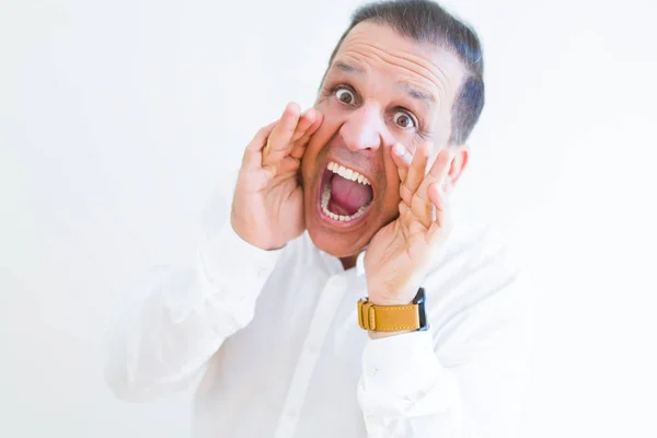Uomo di mezza età gridando pazzo con le mani sulla bocca sopra w bianco — Foto Stock