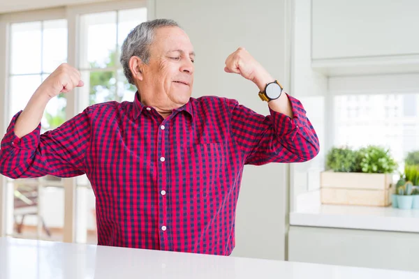 英俊的老人在家里表现出手臂肌肉微笑骄傲 健身理念 — 图库照片