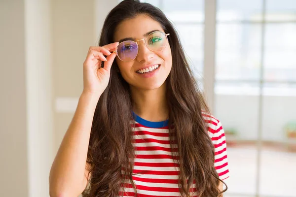 Jonge mooie vrouw glimlachend vrolijk dragen van glazen op zoek h — Stockfoto